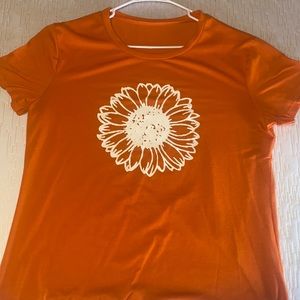 Orange t-shirt with a white flower on it.
